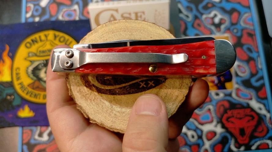 Red pocket knife held by a hand with colorful background