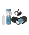 A UCO camping lantern set in light blue, black, and white, featuring the lit lantern, its foam-cushioned carrying case, a white candle, and a metallic reflector on a plain white background.